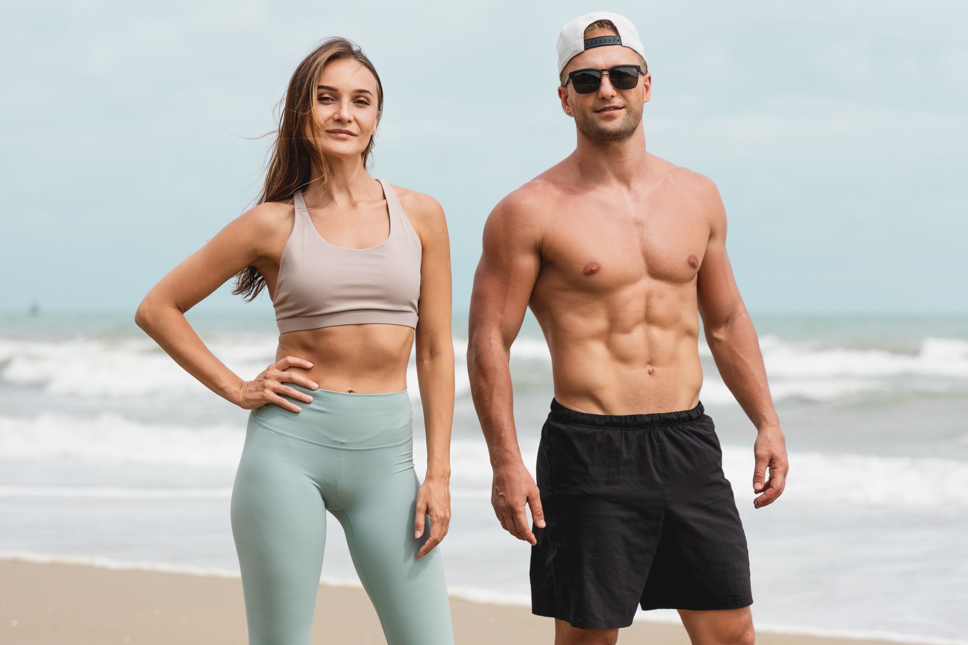 Portraits of Cheerful male and female athlete standing together at seaside. Healthy men and women pose for sexy poses and show off their muscles in the summer day.